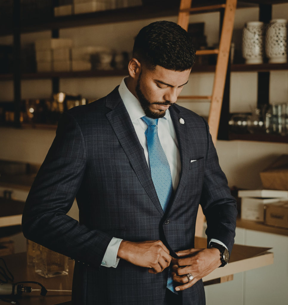 Man doing up the buttons on his suit jacket.